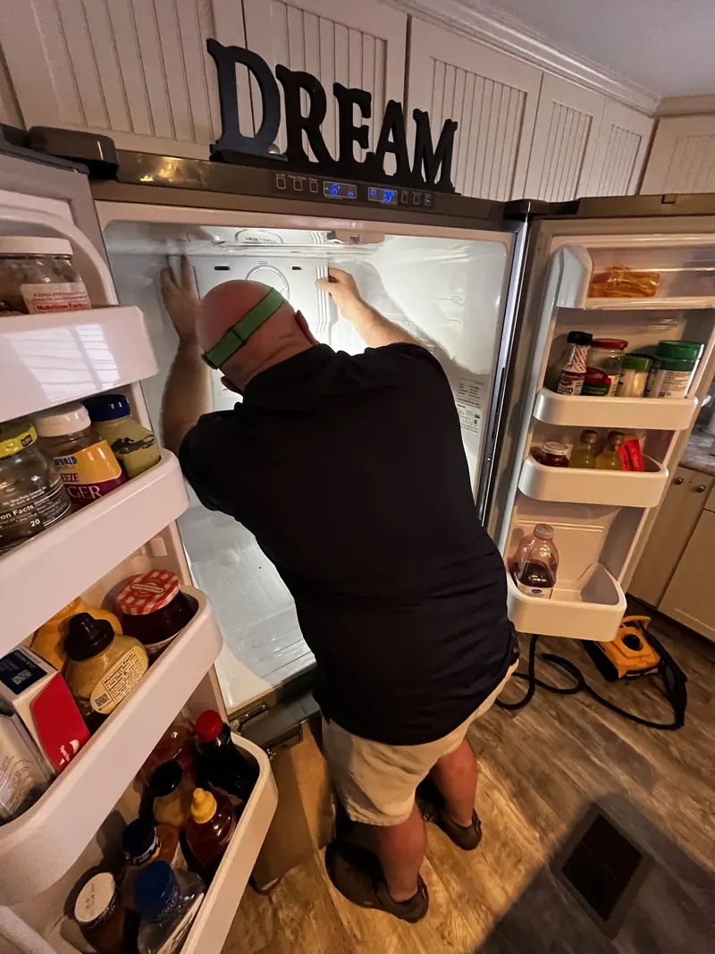 Technician working inside a side-by-side refrigerator